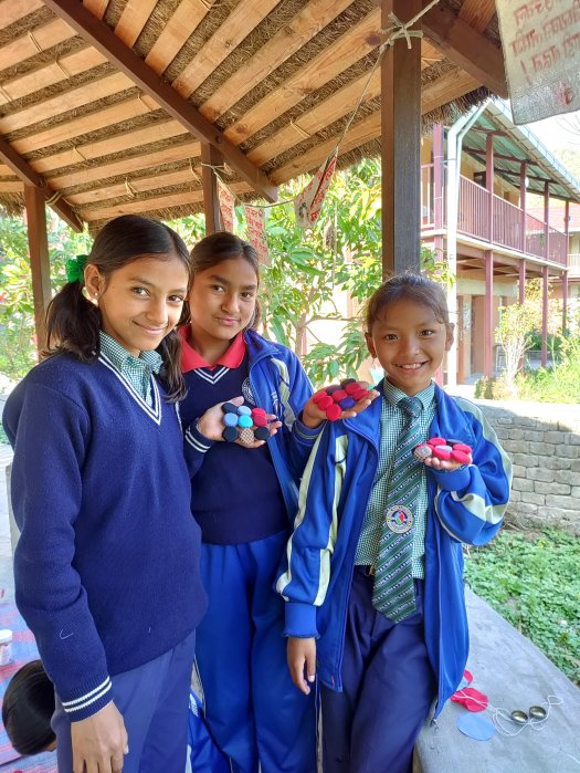 A group of girls shows off their upcycled bottle cap artwork.