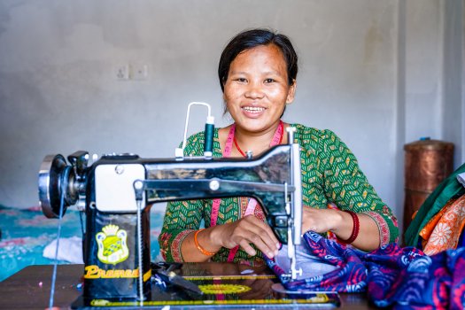 A smiling woman poses with a sewing machine.
