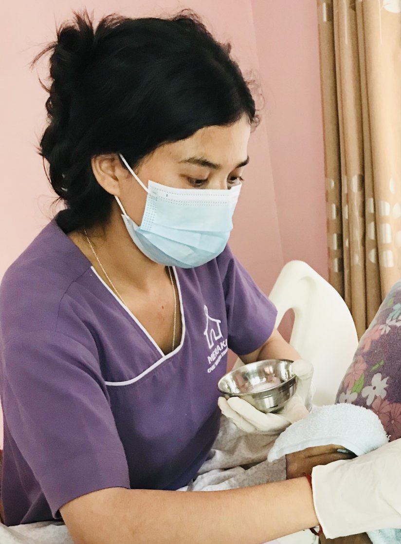 A young woman in nurse's attire holds gauze and is preparing to help a patient.